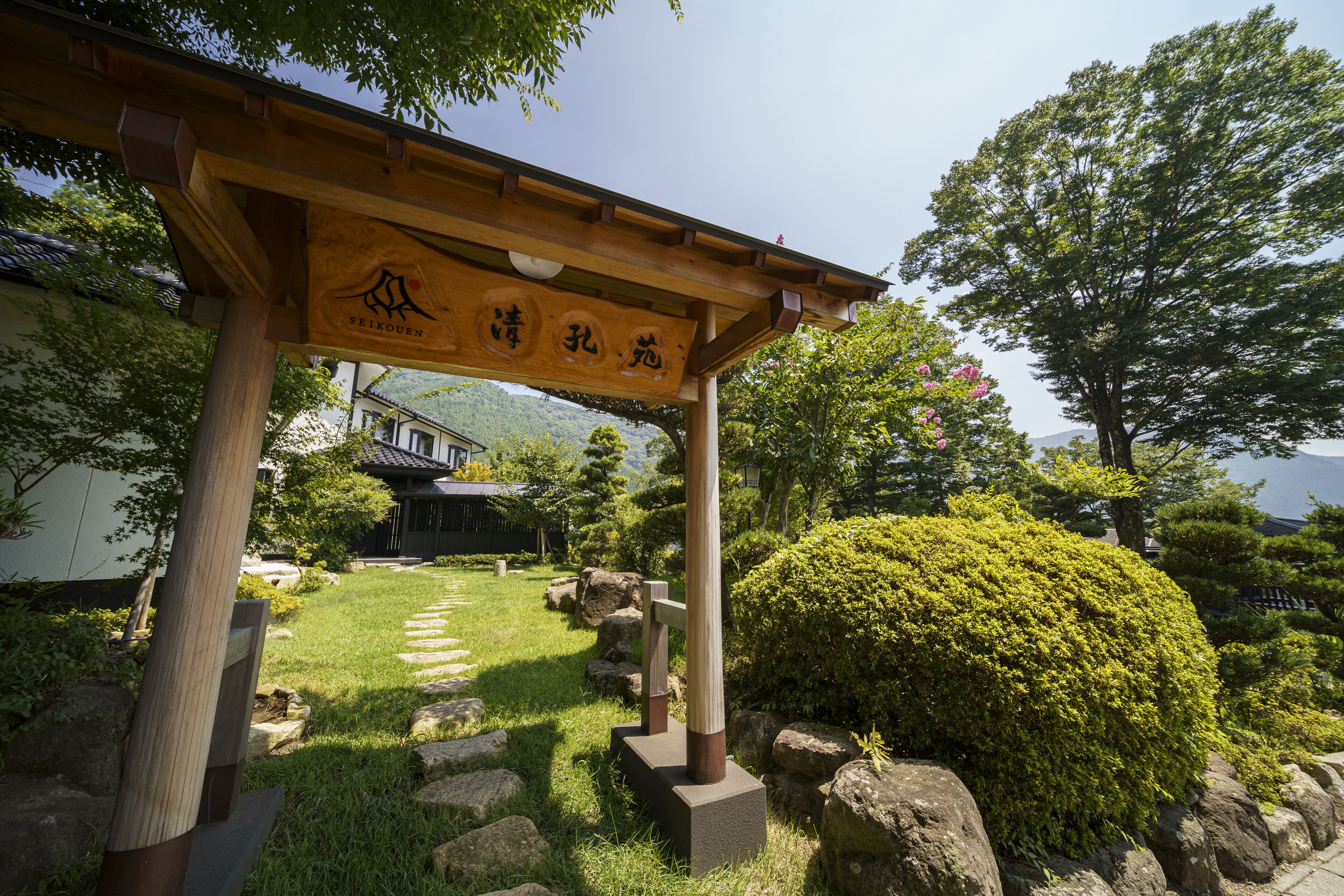 A traditional Japanese garden with a wooden torii gate, stone lanterns, and a well-maintained lawn.
