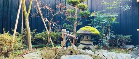 A Japanese garden with a rock arrangement, a stone lantern, and various plants.