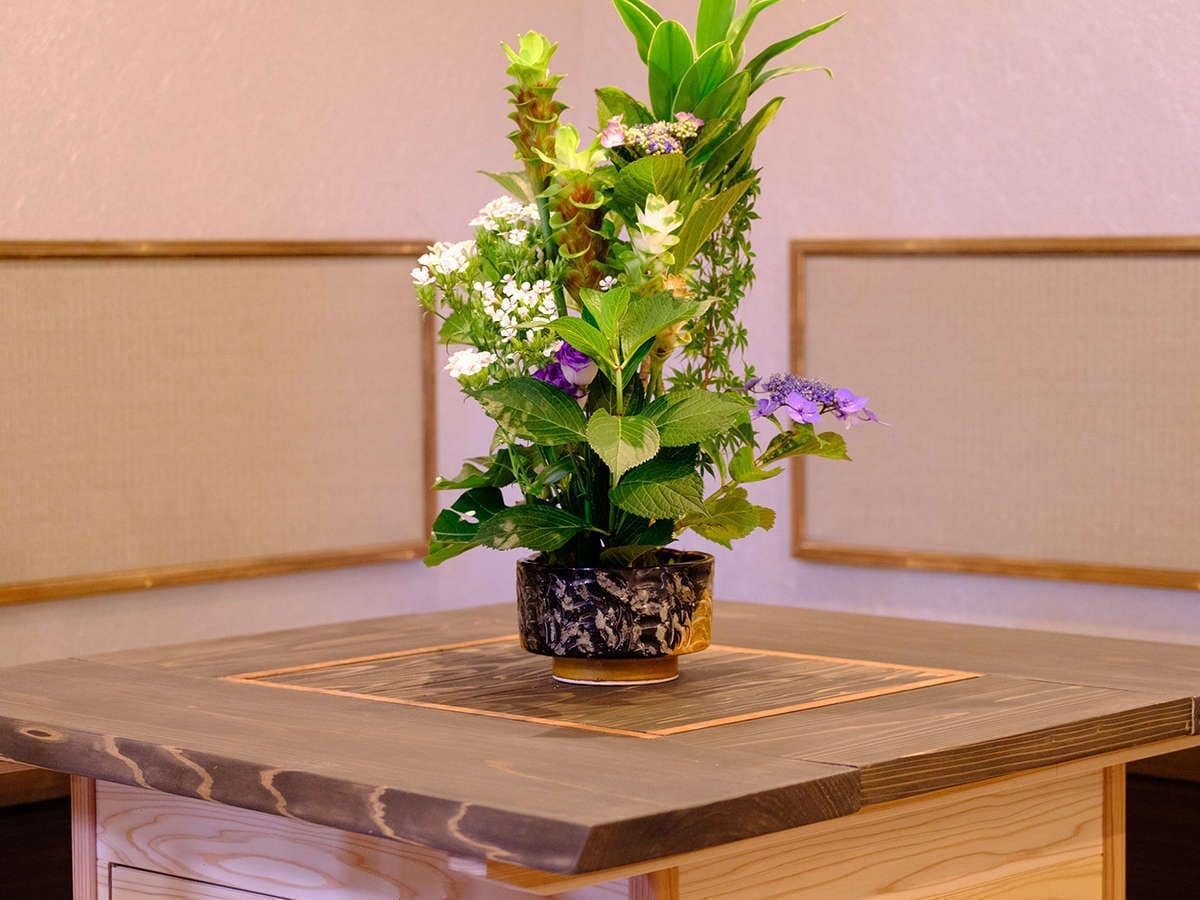 A wooden table with a potted plant in the center.