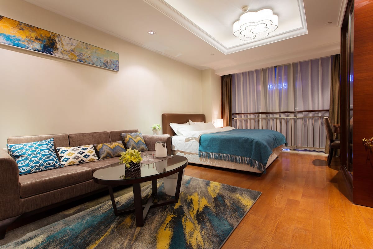 Ein Hotelzimmer mit einer Couch, einem Bett, einem Couchtisch und einem großen Gemälde an der Wand.