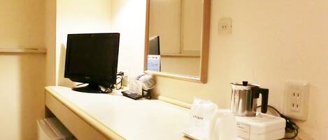 A hotel bathroom with a sink, mirror, and a black television on the counter.