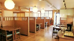 A restaurant with wooden booths and tables, recessed lighting, and a view of the street outside.