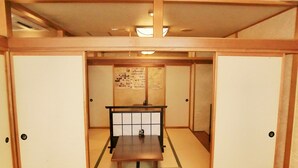 A traditional Japanese room with tatami flooring, a low table, and sliding doors.