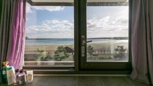 Ein Zimmer mit einer großen Schiebeglastür und Blick auf einen Strand.