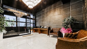 A modern lobby with a chandelier, leather armchairs, a reception desk, and large windows. - SOYU Hotel (Busan)