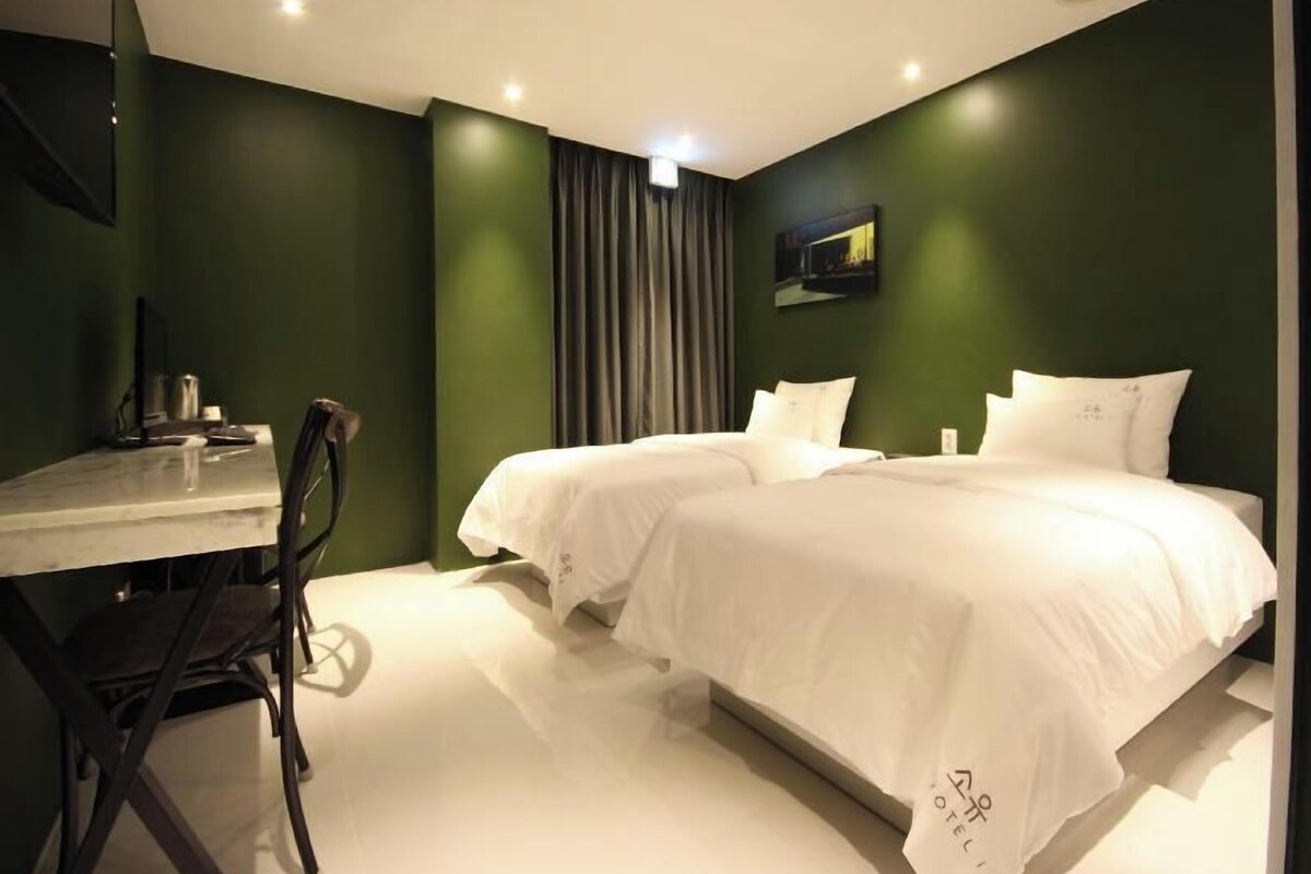 A hotel room with two beds, a desk, and a chair.