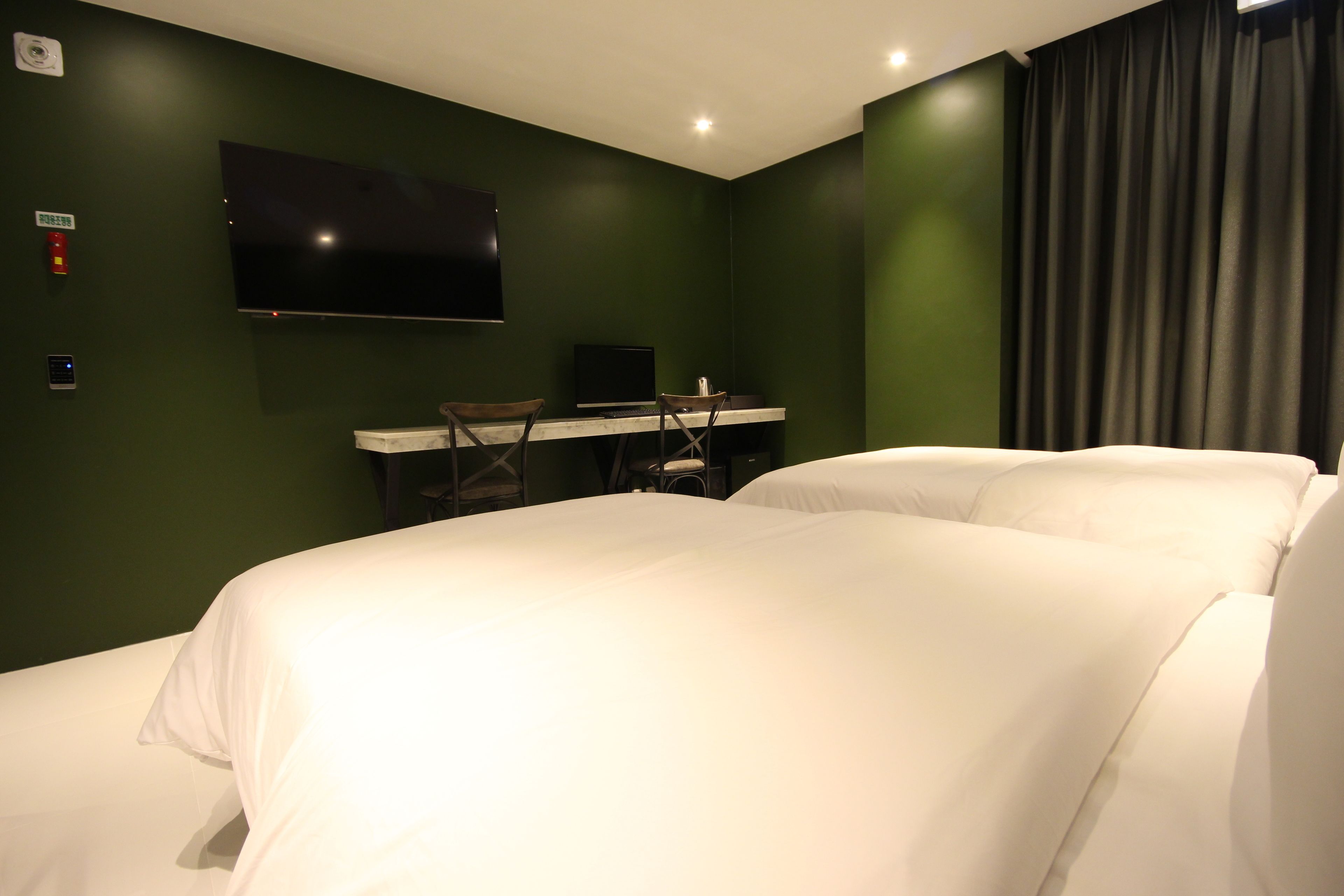 Una habitación de hotel con una cama, un escritorio con una computadora, un televisor y una cortina.