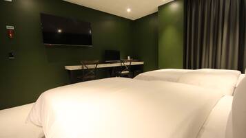 Una habitación de hotel con una cama, un escritorio con una computadora, un televisor y una cortina.