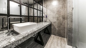 A modern bathroom with a large sink, a glass shower enclosure, and a marble countertop. - SOYU Hotel (Busan)