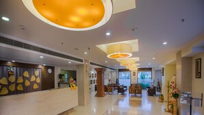 Um hall de hotel com balcão de recepção, área de estar e um pilar grande.