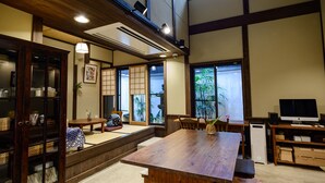 A traditional Japanese-style room with tatami flooring, a low wooden table, and a television on a wooden stand. - Luck You Kyoto (Kyoto)