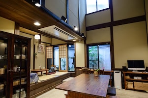 Une pièce de style japonais traditionnel, avec un sol recouvert de tatamis, une petite table en bois et un téléviseur posé sur un meuble en bois.