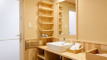 A modern bathroom with a wooden vanity, a large mirror, and built-in shelves.