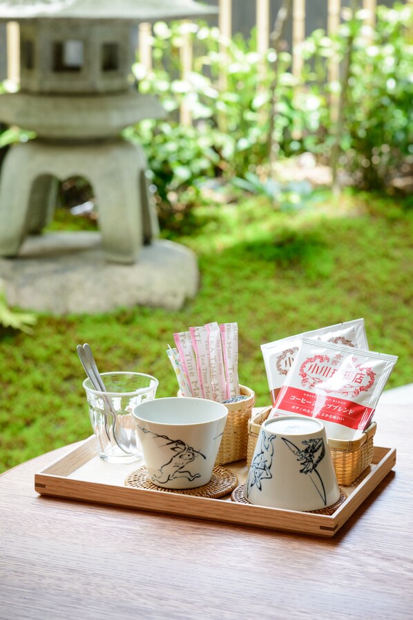 A tray with a teapot, cups, and tea bags on a table with a garden view. - Luck You Kyoto (Kyoto)