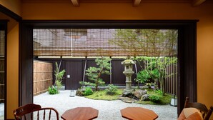 A traditional Japanese-style room with tatami flooring, a low table, and two chairs. - Luck You Kyoto (Kyoto)