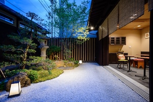 Un jardín tradicional japonés con un sendero de grava, rocas y plantas.