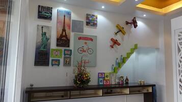 Uma área de recepção com design moderno, apresentando uma escadaria, diversas fotos emolduradas e um painel decorativo com um relógio e uma placa com a frase 'Riding makes the world go round'.