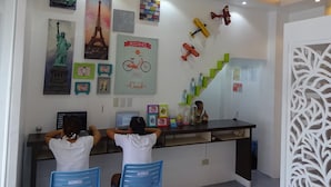 A room with a desk, two chairs, and a wall decorated with various travel-themed posters and a staircase with bottles. - Shejoje Poshtel Hostel (Cebu City)