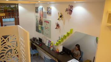 A reception desk with a laptop, a telephone, and various items on the counter. There are posters and a small airplane model on the wall.