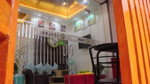A modern interior with a glass partition, a sofa, a red chair, and a wall with a sign reading "SHE JOJE OPEN". - Shejoje Poshtel Hostel (Cebu City)