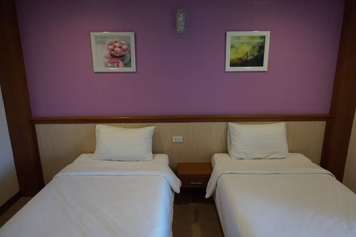 Una habitación de hotel con dos camas, un cabecero de madera y dos cuadros en la pared.