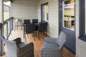 A covered outdoor seating area with a table and chairs, a grill, and wicker furniture. - Holiday Club Himos Superior Apartments (Jamsa)