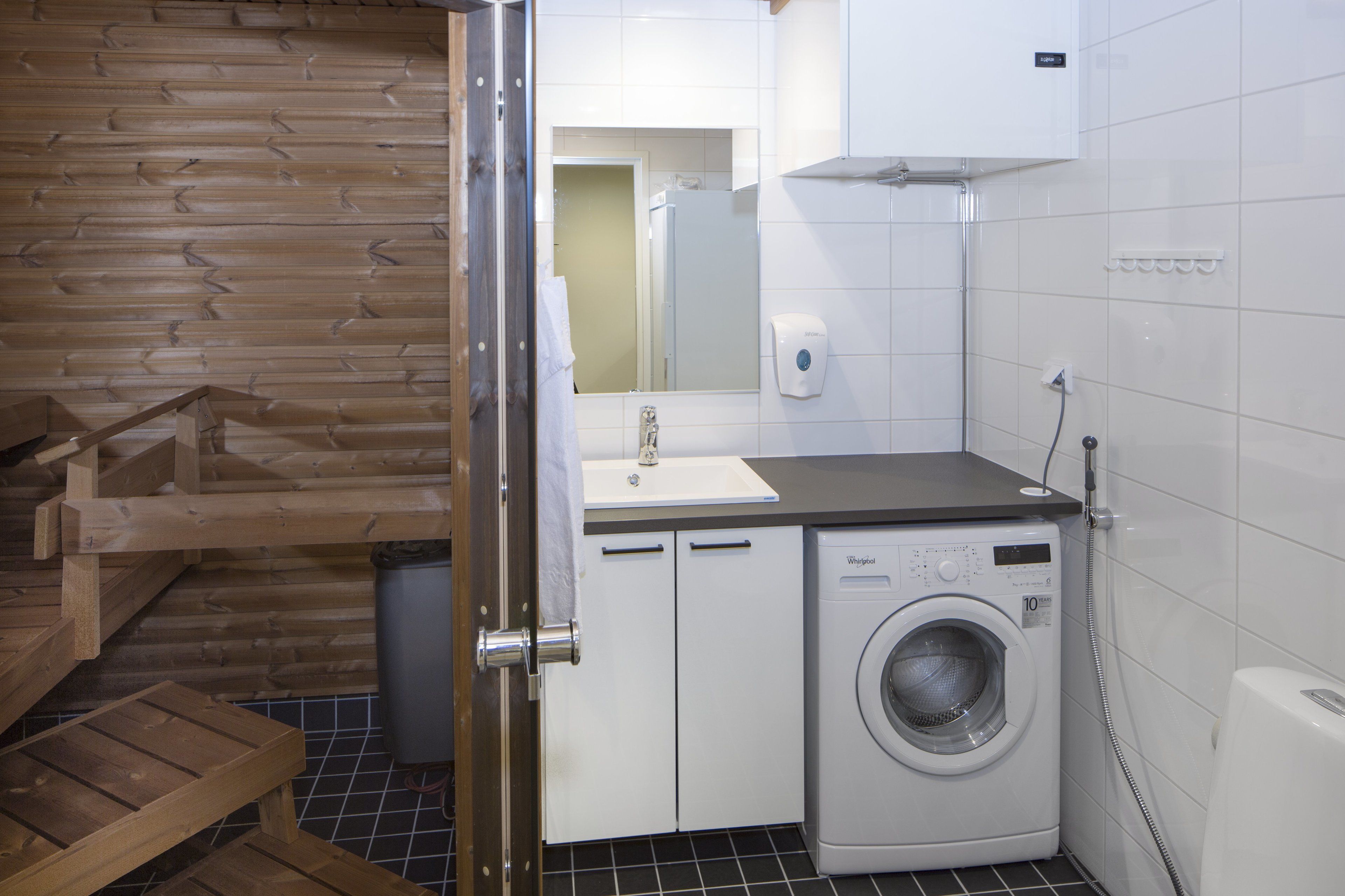 A compact laundry area with a washing machine, a sink, and a mirror.