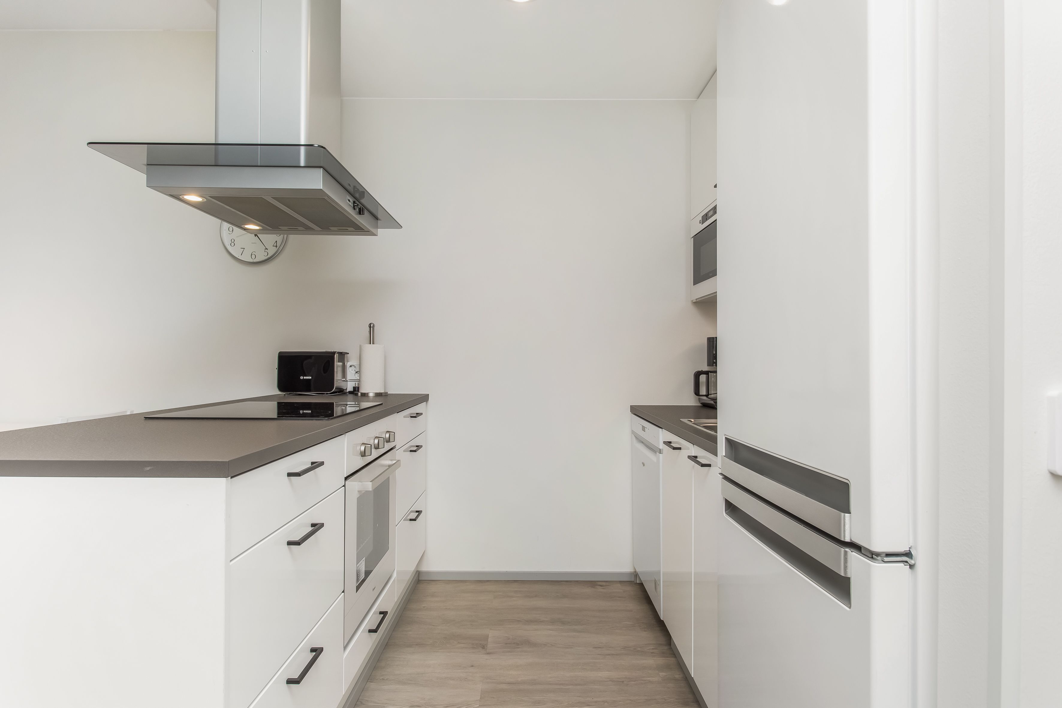 A compact kitchen with a microwave, oven, and stainless steel range hood.
