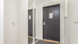 Un couloir avec une porte sombre, une porte vitrée et un hall d’entrée recouvert d’un tapis.