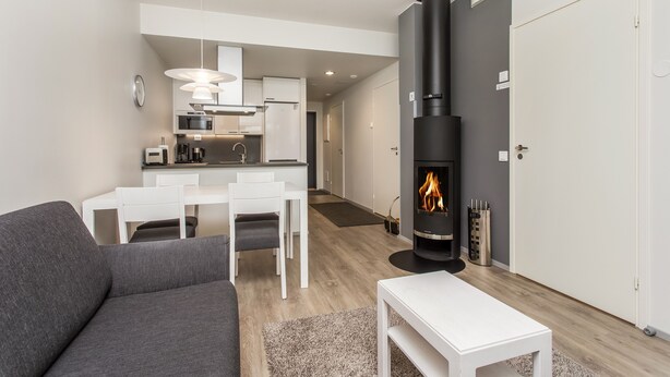 Un salon moderne avec un canapé gris, une table basse blanche et une cuisine en arrière-plan.