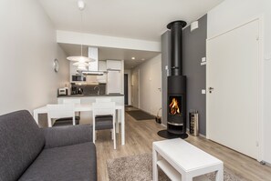 Een moderne woonkamer met een grijze bank, een witte salontafel en een keuken op de achtergrond.