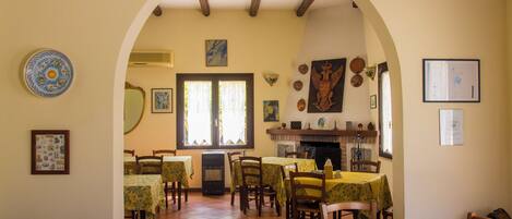 Un comedor con mesas y sillas, una chimenea y diversas decoraciones en las paredes.