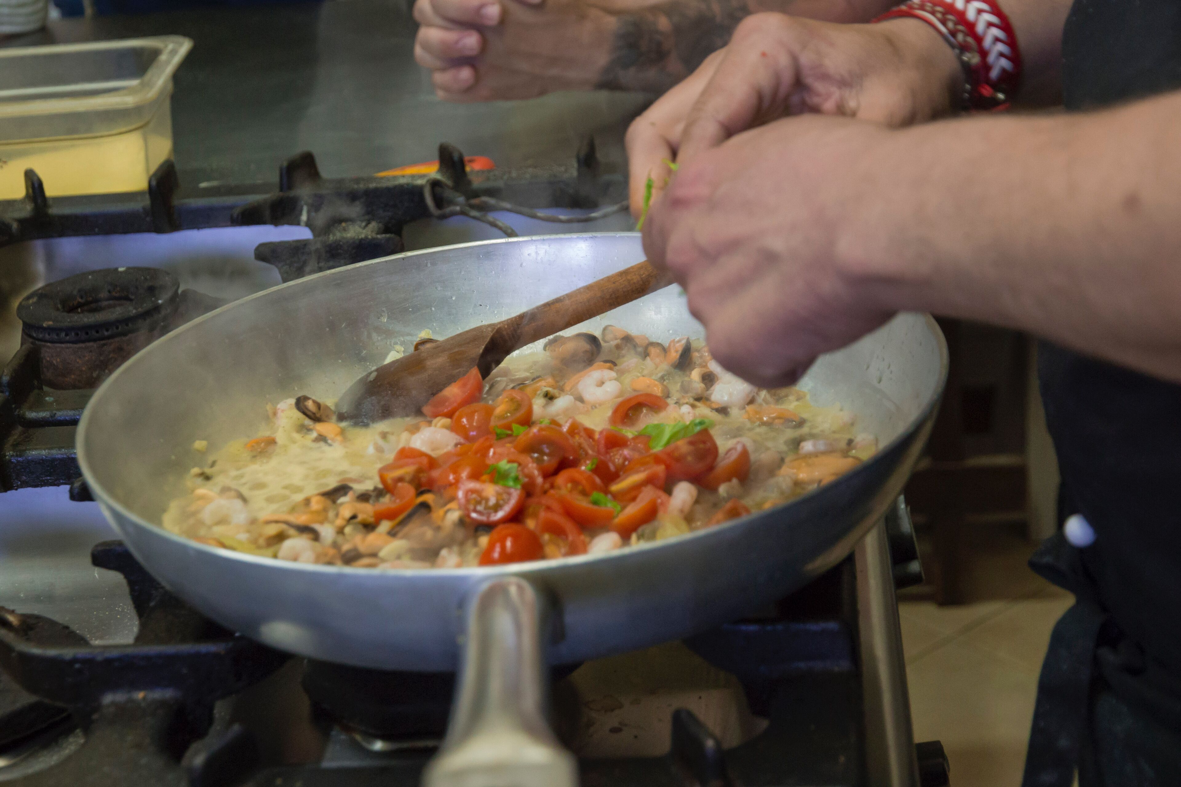 Una persona cucina in una cucina con una padella sul fornello.
