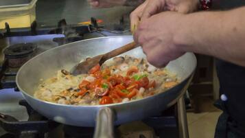 Una persona cucina in una cucina con una padella sul fornello.