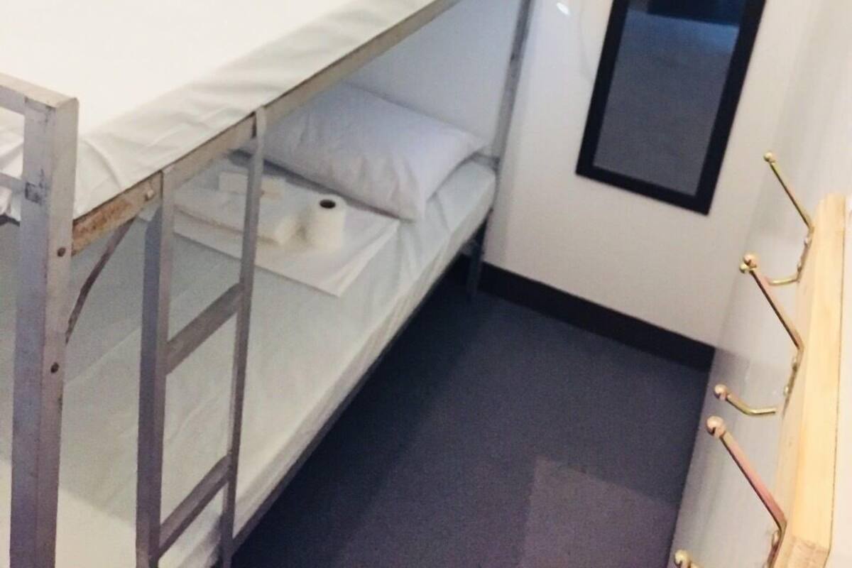 A bunk bed room with a small desk, a mirror, and a door.