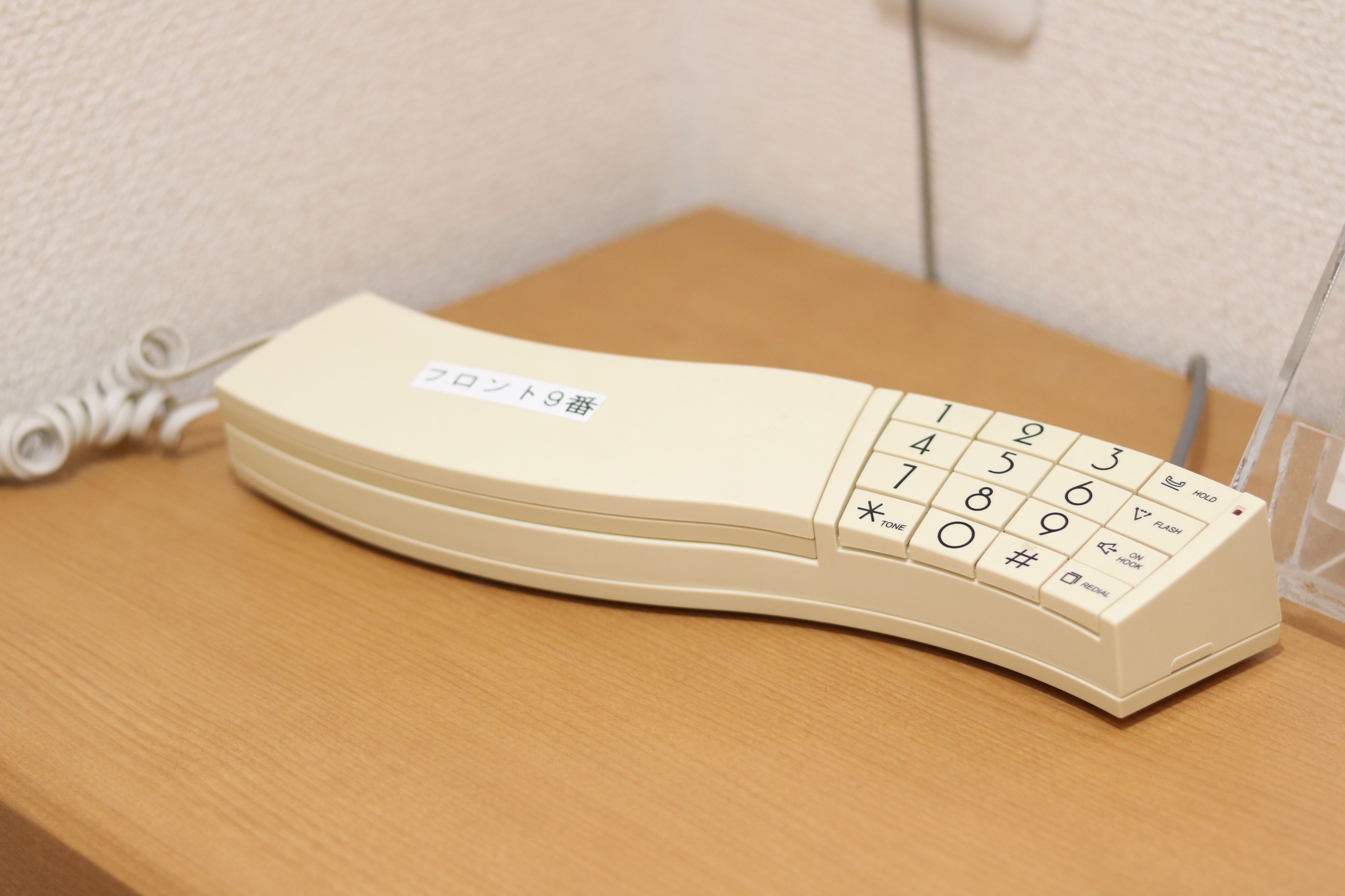 A beige telephone with a numeric keypad and a label in a foreign language.