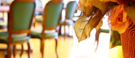 Un comedor con sillas de madera y una mesa con un florero.