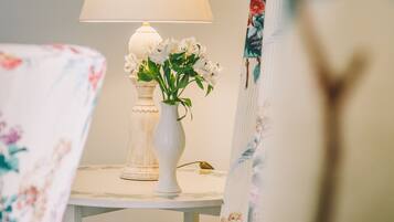 Una habitación con una mesa que tiene una lámpara y un florero con flores.