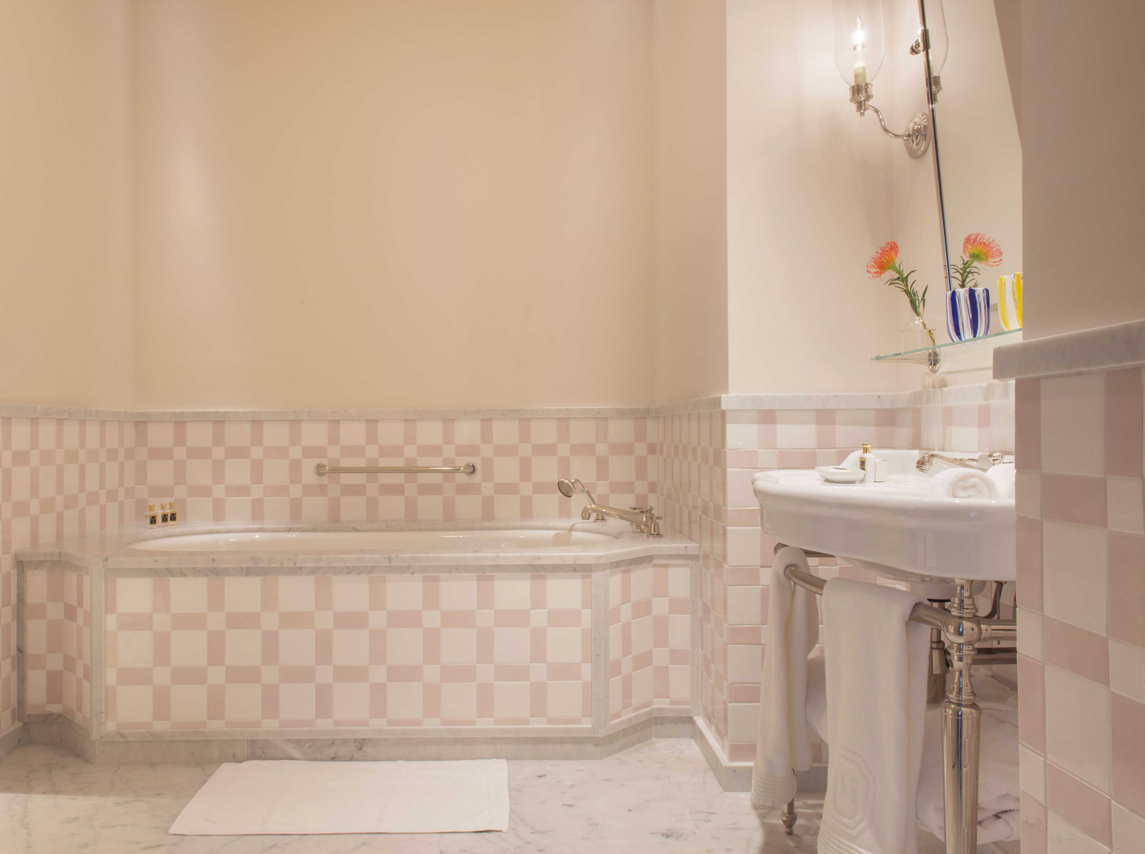 A bathroom with a checkered tile wall, a bathtub, a sink, and a mirror.