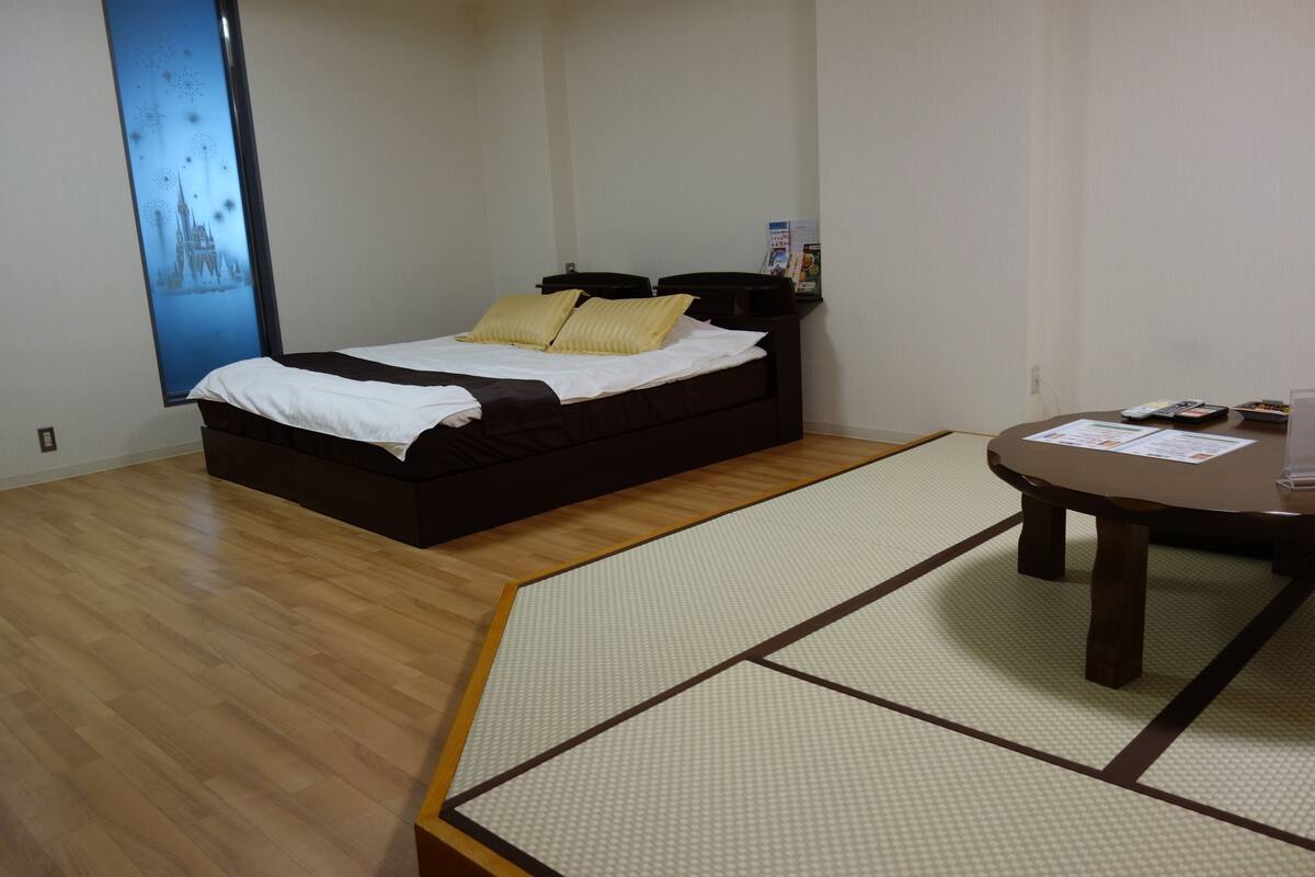 A room with a bed, a small table, and a tatami mat.