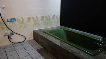 Un baño con un lavabo verde, ducha y piso de baldosas.