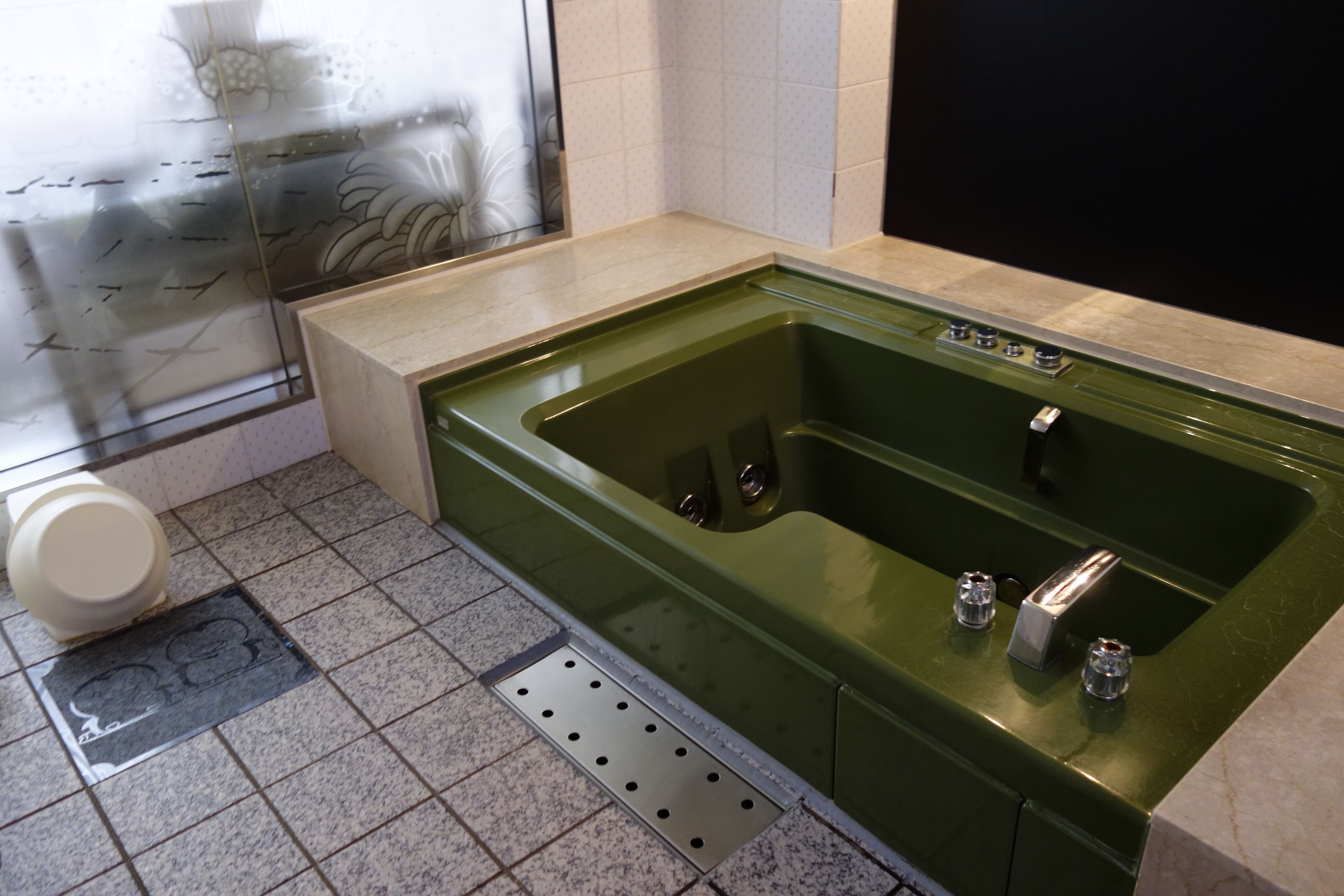 Un baño con una bañera verde, un inodoro y una zona de ducha.