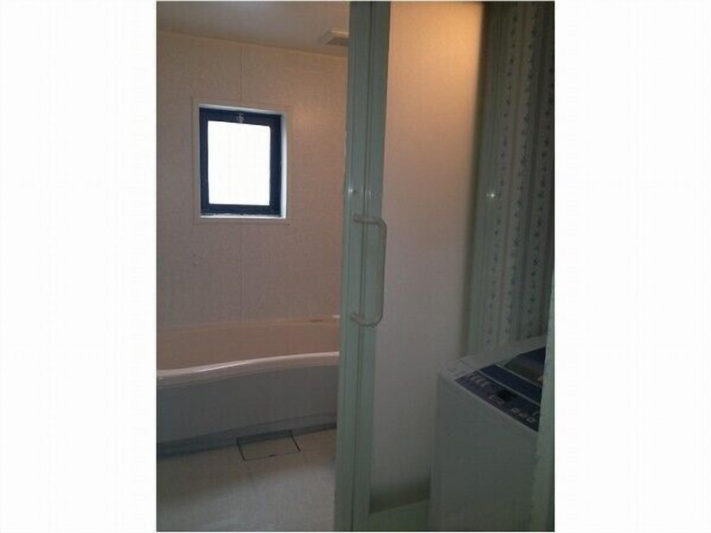 A bathroom with a bathtub, a window, and a toilet.