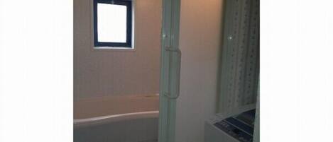 A bathroom with a bathtub, a window, and a toilet.