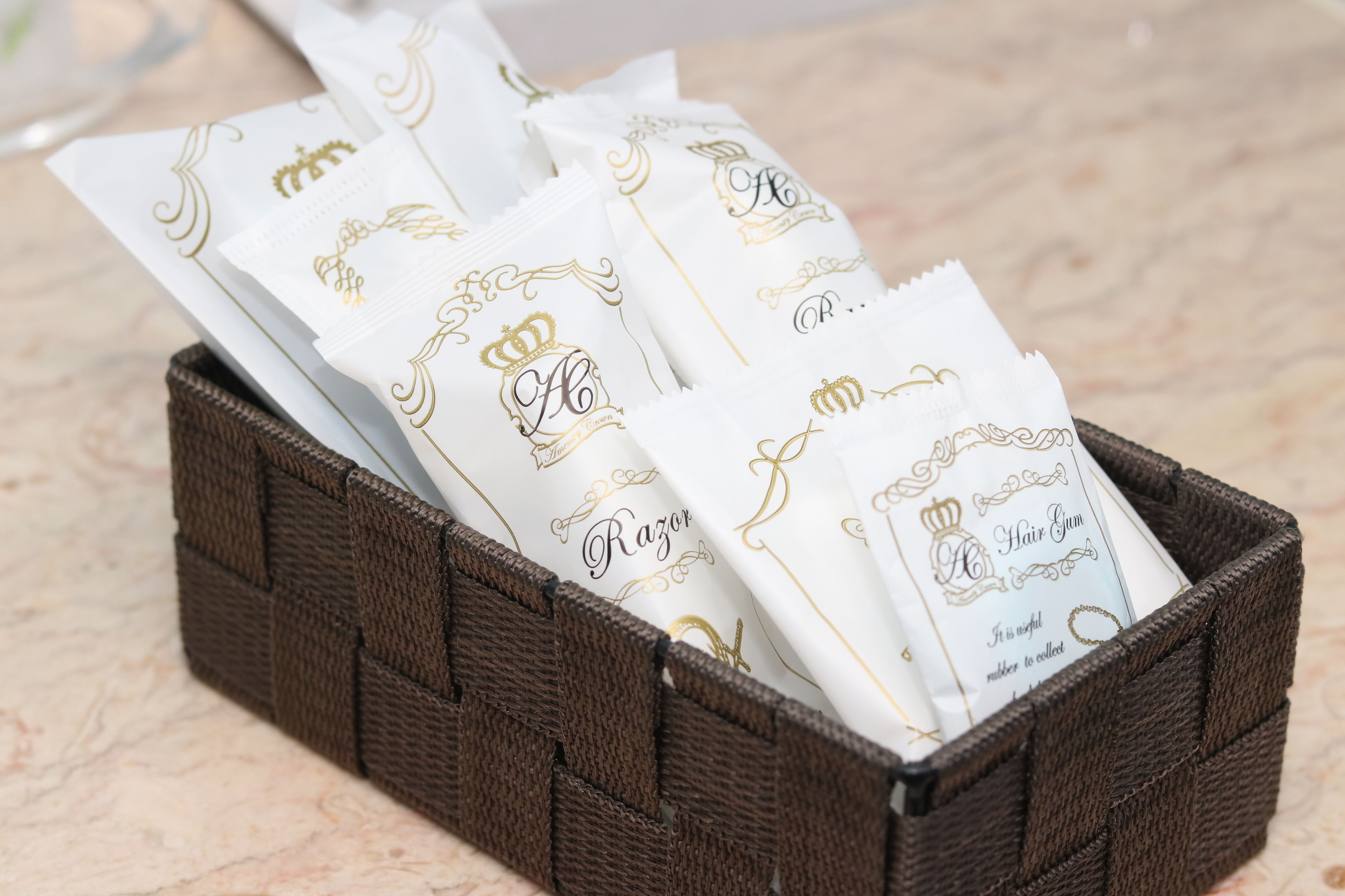Un panier en osier contenant plusieurs paquets blancs ornés de lettres et de motifs dorés.