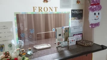 A reception desk with a 'FRONT' sign, a small table with a bottle and a glass, and a decorative item resembling a snowman.