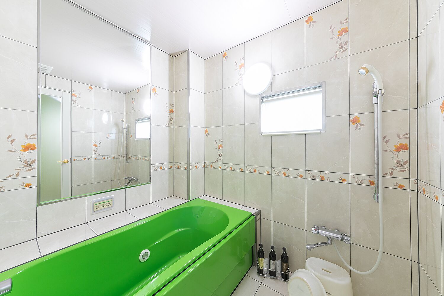 A bathroom with a green bathtub, a toilet, and a shower.