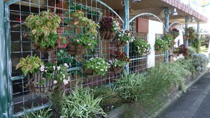 A building with a metal fence adorned with hanging flower baskets. - Hotel To (Wakayama)