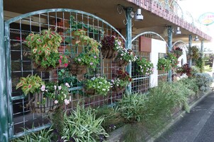 Un edificio con una cerca metálica decorada con macetas colgantes de flores.