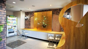A reception area with a vending machine, a decorative wall, and a wooden accent piece. - Hotel To (Wakayama)